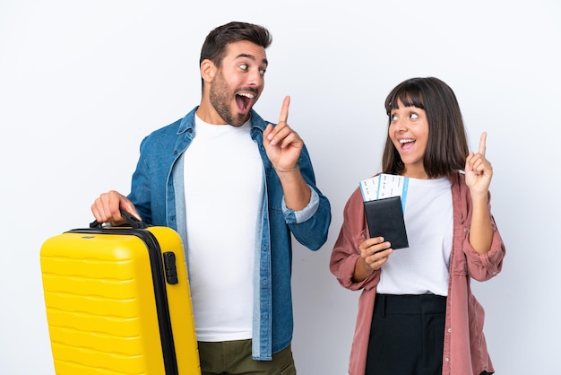 Casal jovem viajante segurando uma mala e passaporte isolado no fundo branco com a intenção de perceber a solução enquanto levanta um dedo