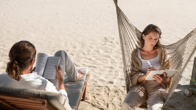 Foto casal lendo livros na praia durante as férias