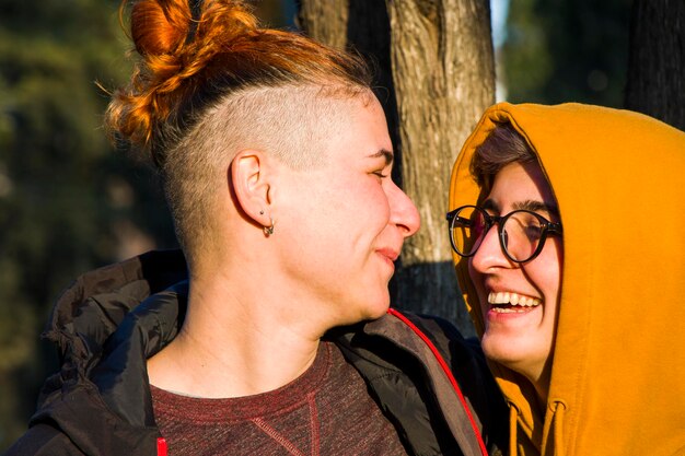 Foto casal lésbico gay retrato de duas mulheres adultas no parque sorrindo e abraçando o pôr do sol