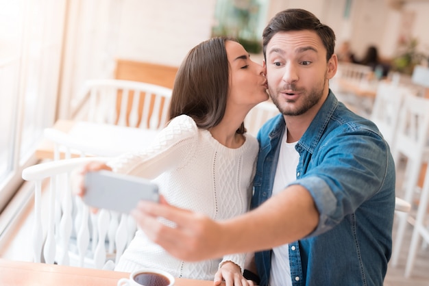 Casal leva selfie no café mulher dá um beijo.