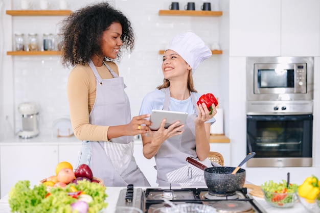 Casal LGBT mulheres amigo atividade de férias usando tecnologia de tablet internet ajuda a aprender a cozinhar comida saudável adorável fofo juntos