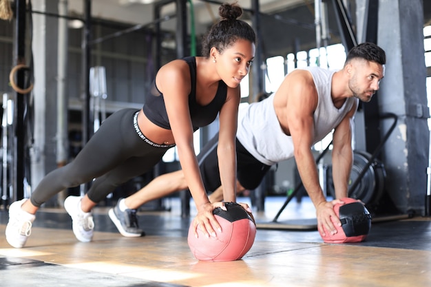 Casal lindo jovem esportes está malhando com medicine ball no ginásio.