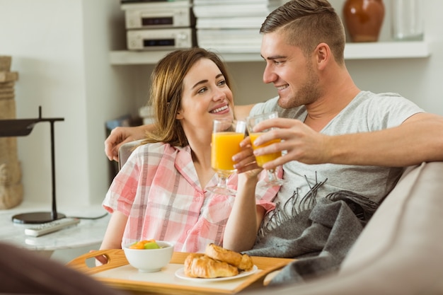 Casal lindo relaxando no sofá com café da manhã