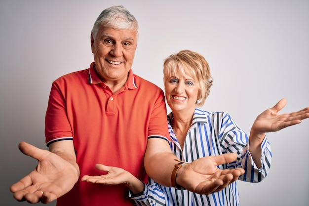 Casal lindo sênior dançando juntos sobre fundo branco isolado sorrindo mostrando as palmas das mãos abertas apresentando e comparando publicidade e equilíbrio