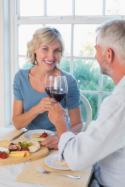 Casal maduro brindando copos de vinho sobre comida