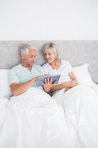 Foto casal maduro com comprimido digital na cama