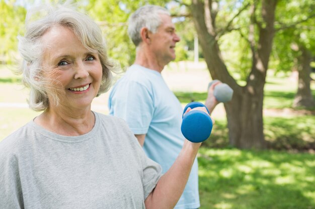 Casal maduro com dumbbells no parque