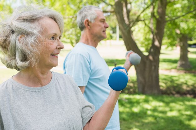 Casal maduro com dumbbells no parque