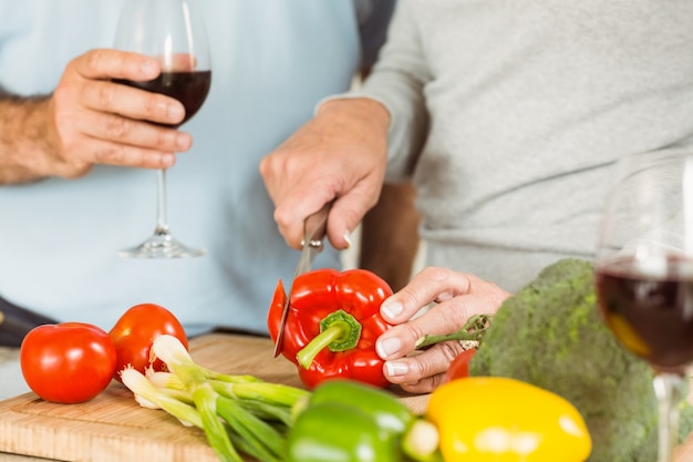 Casal maduro com vinho tinto enquanto faz o jantar