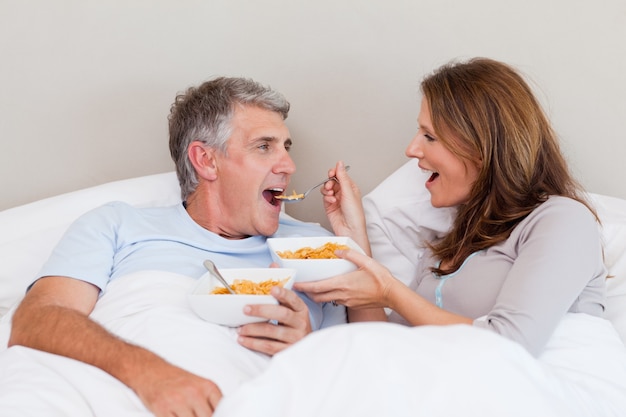 Casal maduro comendo cereais na cama