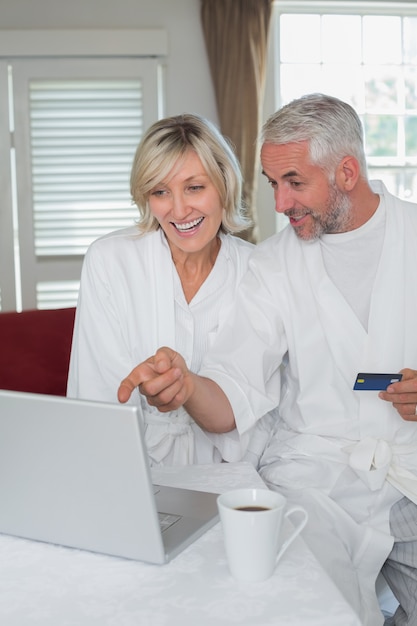 Casal maduro feliz fazendo compras on-line em casa