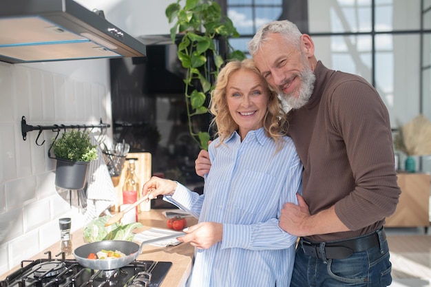 Casal maduro na cozinha parecendo feliz e tranquilo