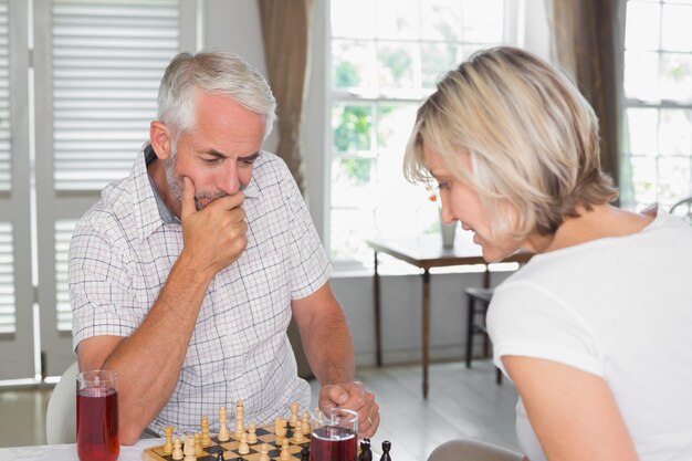 Casal maduro sério jogando xadrez em casa