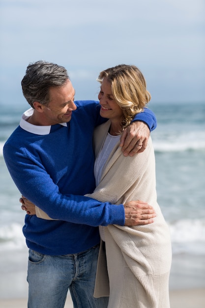 Casal maturo, abraçando-se na praia