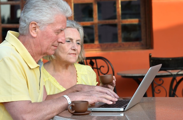 Foto casal maturo sentado com laptop e café no hotel