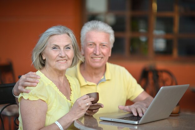 Casal maturo sentado com laptop e café no hotel