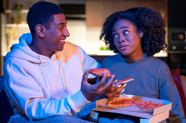 Foto casal mediano comendo pizza