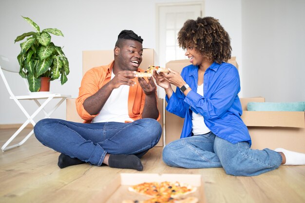 Casal milenar negro com pizza comemorando a mudança para uma nova casa