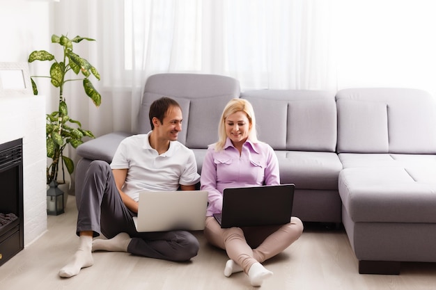 Casal moderno feliz navegando na internet e trabalhando no laptop em casa