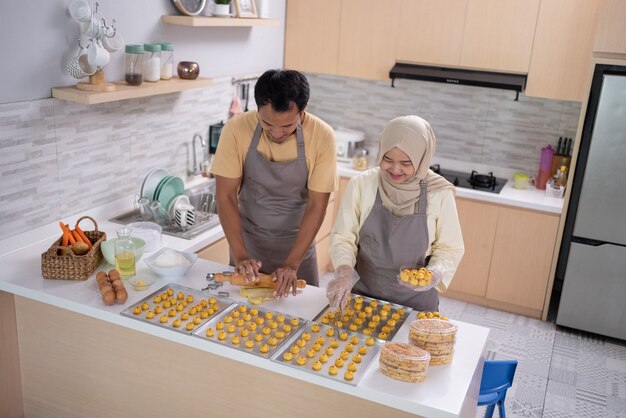 Casal muçulmano asiático fazendo bolo de lanche nastar na cozinha