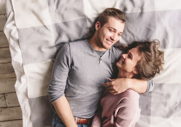 Casal muito amoroso é deleitar-se na cama juntos. Eles estão abraçando e sorrindo