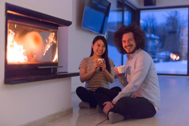 casal multiétnico feliz sentado em frente à lareira