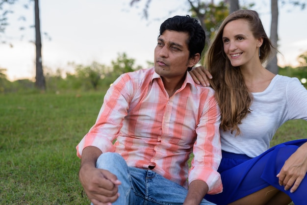 Casal multiétnico feliz sorrindo enquanto pensa