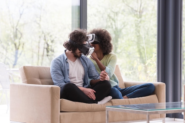 Casal multiétnico usando fone de ouvido de realidade virtual na sala de estar em casa pessoas jogando com a tecnologia de novas tendências