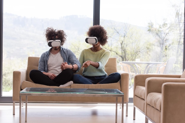 Casal multiétnico usando fone de ouvido de realidade virtual na sala de estar em casa pessoas jogando com a tecnologia de novas tendências