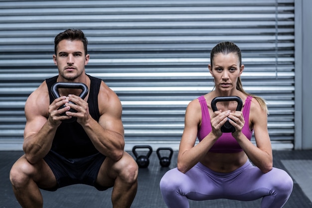 Casal muscular exercitando com kettlebells