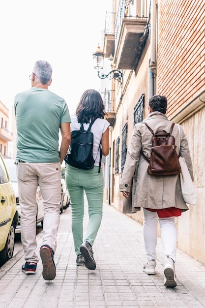 Casal na companhia de uma amiga caminhando para casa