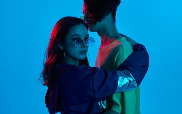 Casal na moda abraçando no estúdio com luz neon