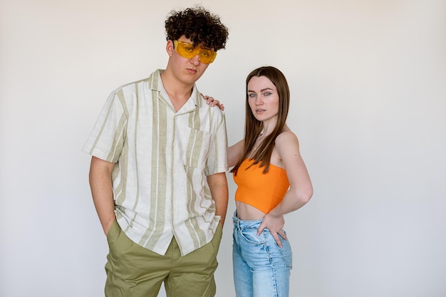 Casal na moda posando e vestindo roupas e acessórios sazonais para homens e mulheres de costas brancas