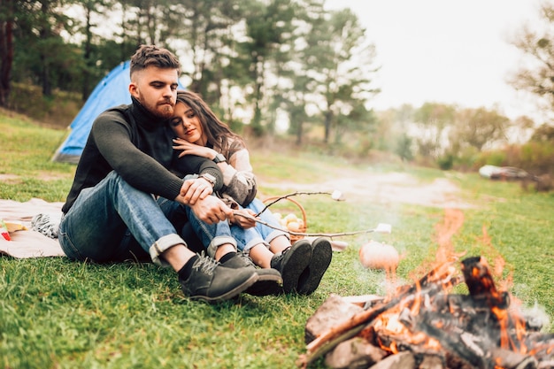 Casal na natureza assando marshmallows