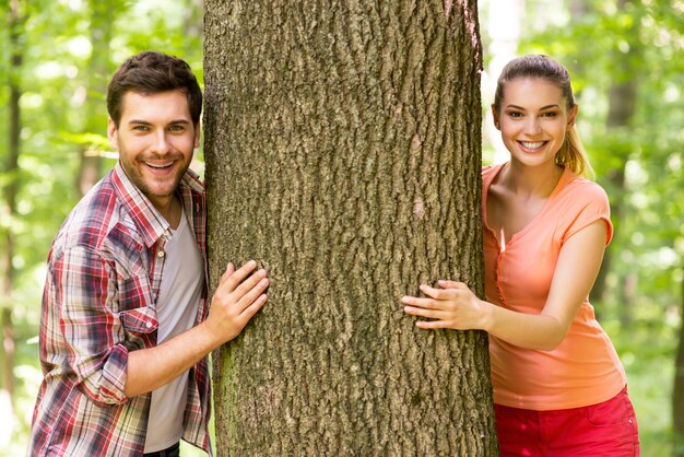 Casal na natureza. Jovem casal lindo olhando para fora da árvore e sorrindo em um parque