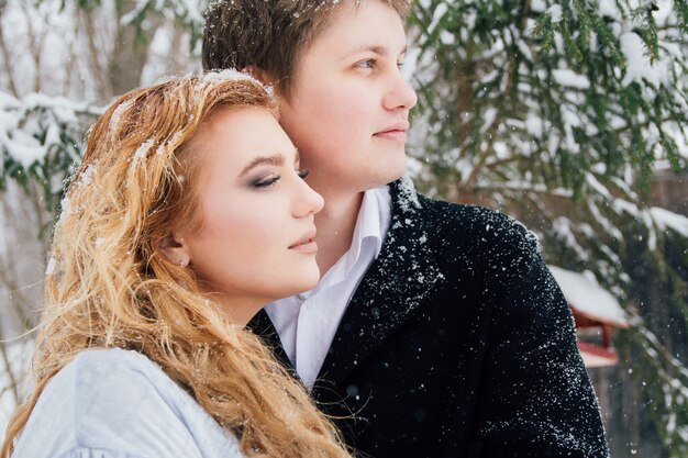 Casal na natureza no inverno durante uma queda de neve