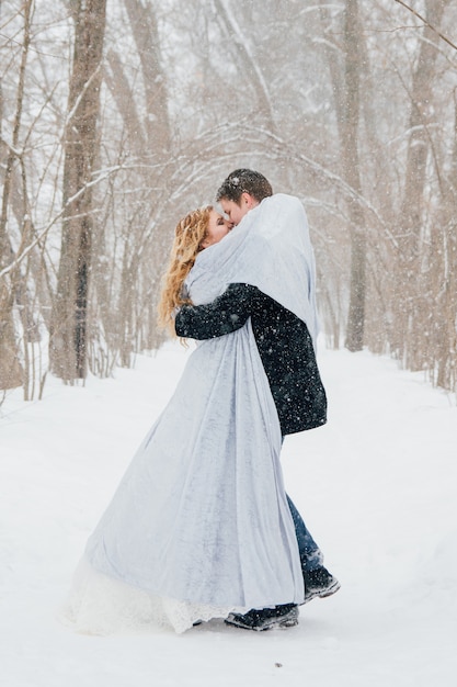 Casal na natureza no inverno durante uma queda de neve