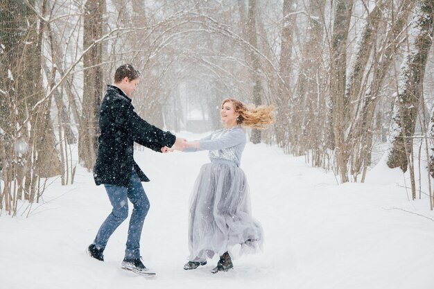 Casal na natureza no inverno durante uma queda de neve