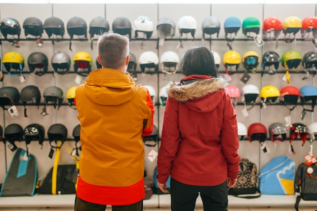 Casal na vitrine escolhendo capacetes para esqui ou snowboard