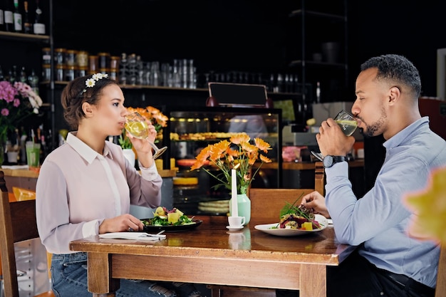 Casal negro americano em um encontro bebe vinho em um restaurante.