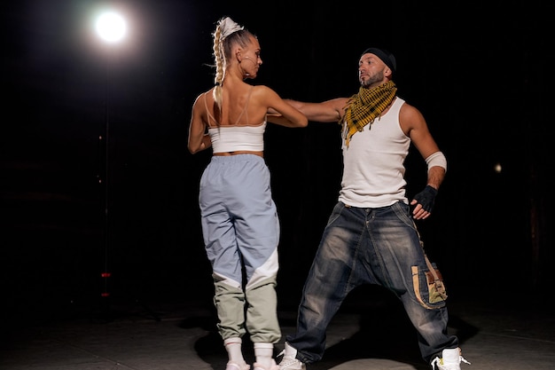 Casal negro e caucasiano dançando a dança contemporânea em fundo studio.black. Lições de dança. Performance de dança Hip Hop no palco. Homem e mulher fazendo apresentações juntas, dançando no estilo hip hop