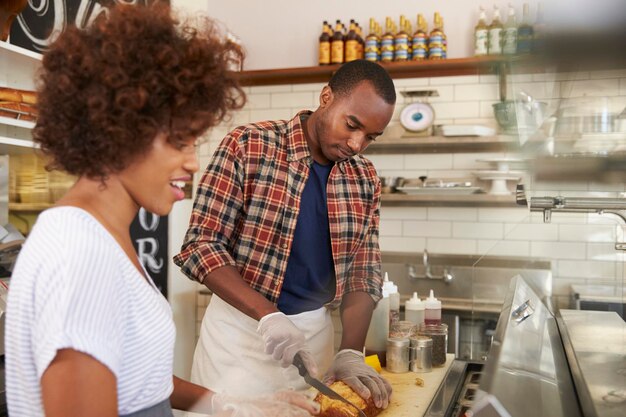 Casal negro prepara comida atrás do balcão em uma lanchonete