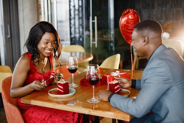 Casal negro romântico sentado no restaurante vestindo roupas elegantes