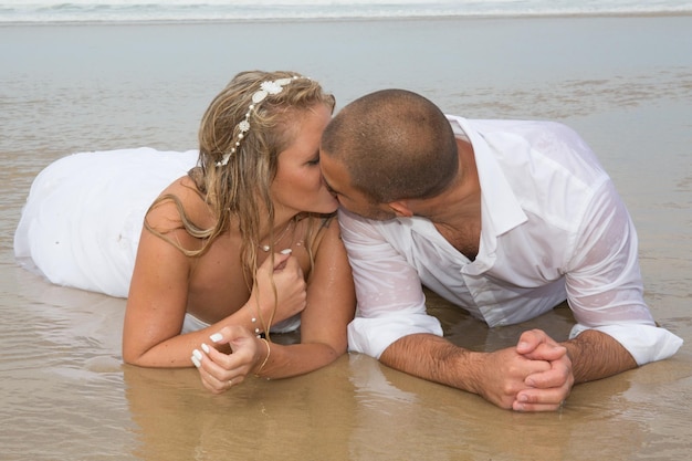 casal no dia do casamento beijo na água mar praia