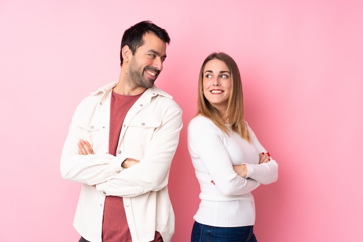 Foto casal no dia dos namorados sobre parede rosa isolada, olhando por cima do ombro com um sorriso