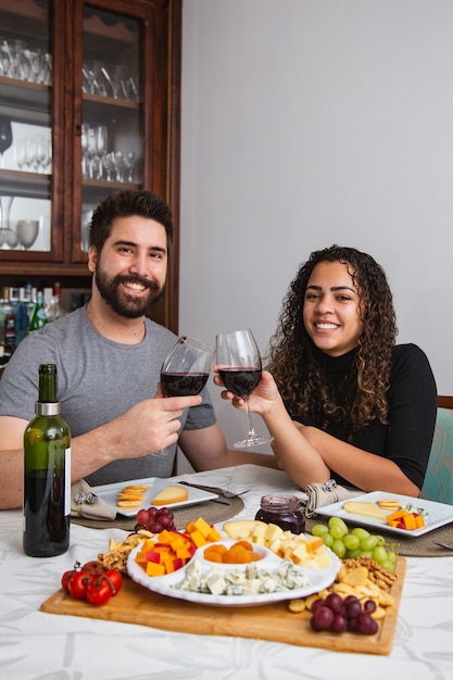 Foto casal no jantar romântico degustação de vinho e queijo. casal com petiscos de vinho e queijo no inverno. vertical