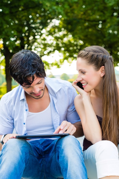 Casal no parque da cidade com computador tablet