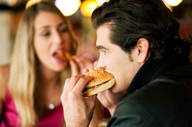 Foto casal no restaurante comendo fast-food