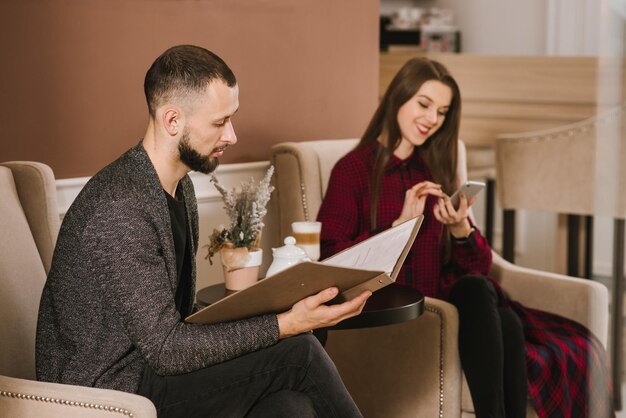 Casal no restaurante e homem lendo um menu