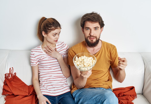 Casal no sofá pipoca assistindo tv dentro de casa homem mulher